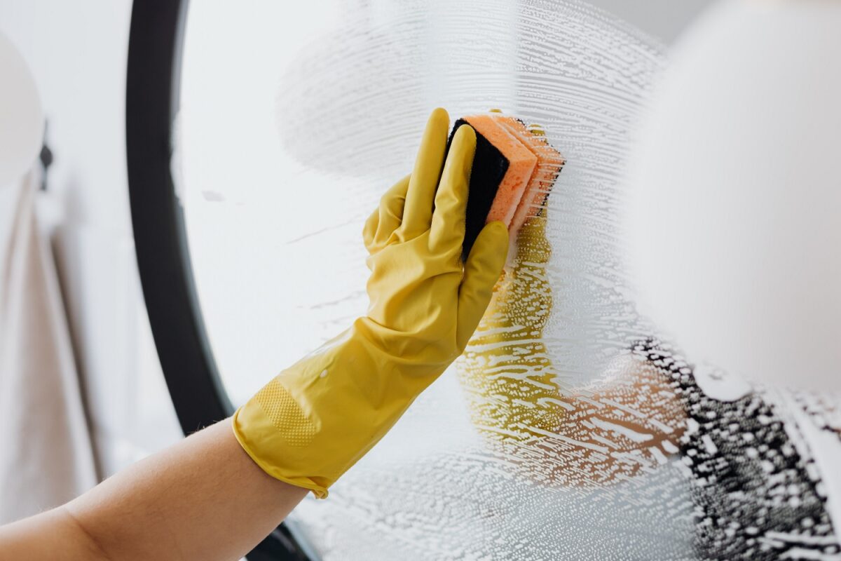 Person cleaning mirror with sponge