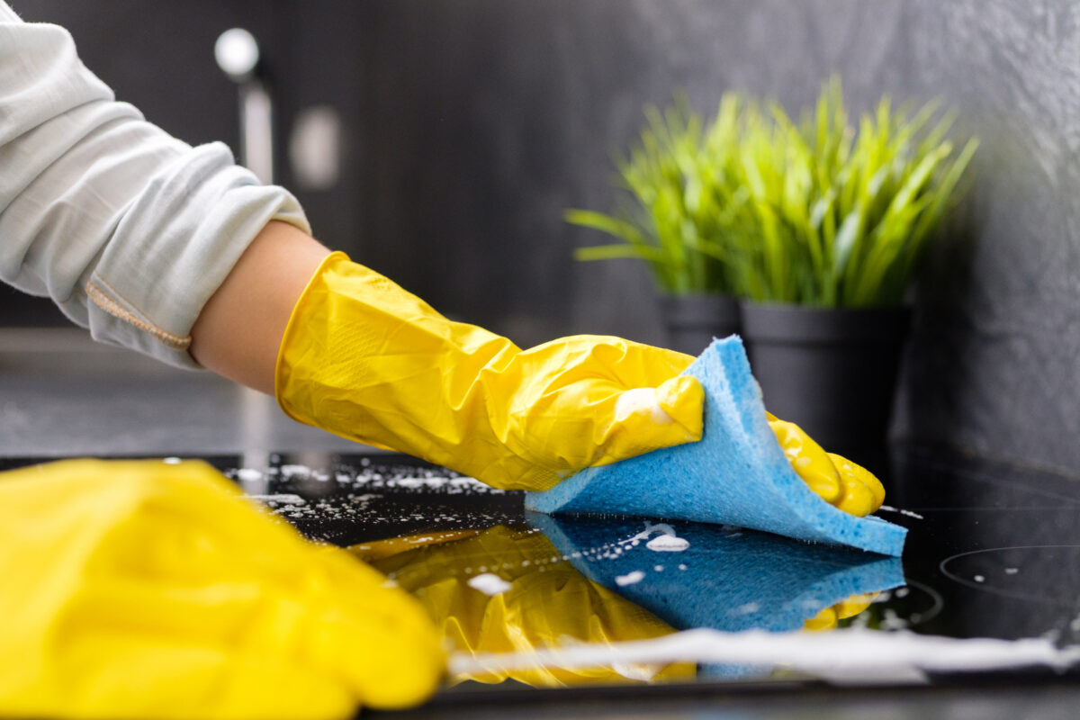 person cleaning with gloves on stovetop